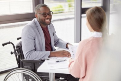 A man, who is seated in a wheelchair, at the table with a women, who has papers in her hand., McGrath Law Firm, Personal Injury, Mt. Pleasant, SC.
