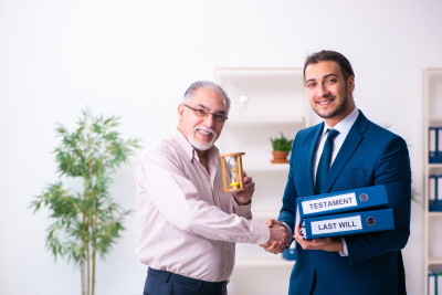 A young lawyer, holding a Last Will and Testament Binders in his left hand, shaking he hand of an older gentlemen, who is holding an hour glass in his left hand.., McGrath Law Firm, Family Law, including Last Will & Testaments, Mt. Pleasant, SC